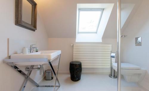 baño con lavabo y aseo y ventana en La Maison Les Mimosas, en Le Minihic-sur-Rance