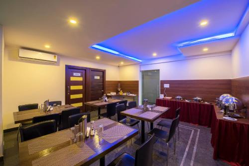 a dining room with tables and chairs and blue lights at Daffodil Delight - Manyata Tech Park in Bengaluru