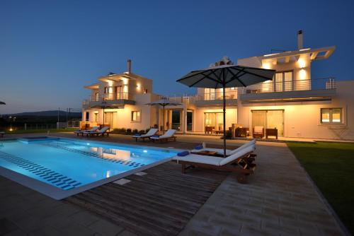 a villa with a swimming pool in front of a house at Edem Suites in Marathopolis