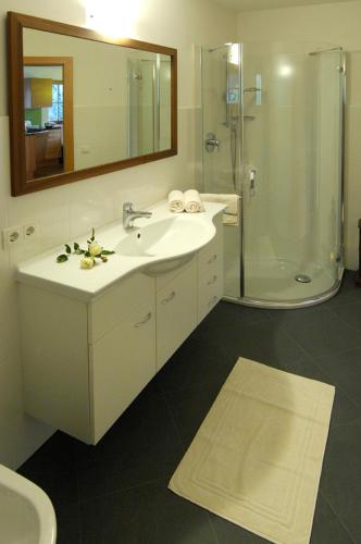 a bathroom with a sink and a shower with a mirror at Villa Tilia in Siusi