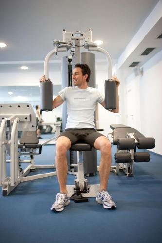 a man is sitting on a gym machine at Hotel Grüner Baum in Bressanone