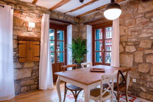 una mesa y sillas en una habitación con una pared de piedra en Apartamento Carlos V, en Hondarribia