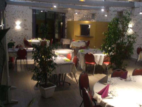 une salle à manger avec tables, chaises et plantes dans l'établissement Le Relais, à Saint-Quentin-les-Anges