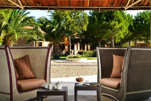 two wicker chairs and tables on a patio with trees at Fattoria San Lorenzo in Grosseto