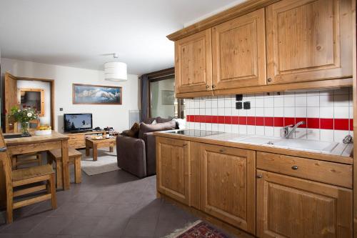 a kitchen with wooden cabinets and a living room at Le Paradis ski apartment - Chamonix All Year in Chamonix