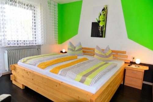a bedroom with a wooden bed with green walls at Pension Erika in Mehlmeisel