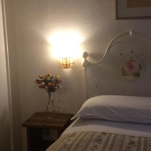 a bedroom with a bed with a lamp and a vase of flowers at Villa Fedora in Lizzano in Belvedere