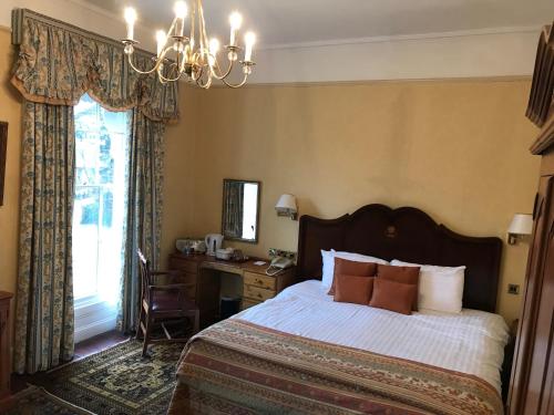 a bedroom with a bed and a desk and a window at Stower Grange Hotel in Norwich