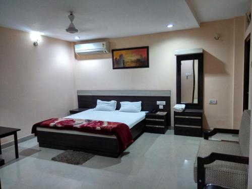 a bedroom with a bed and a table and a mirror at Hotel Raj Palace in Dibrugarh