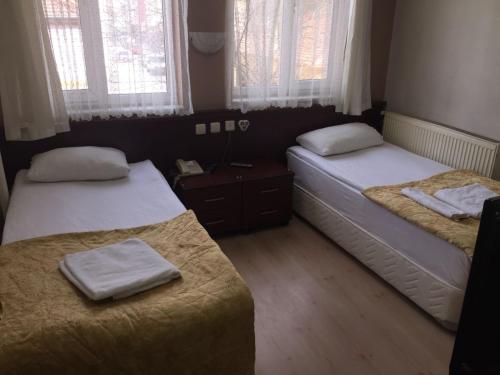 a bedroom with two beds and two windows at Sirin Hotel in Corum