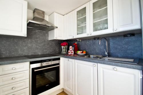 une cuisine avec des armoires blanches et un évier dans l'établissement Victoria, à Cannes