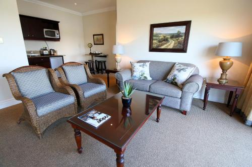 a living room with a couch and two chairs and a table at Kingfisher Lodge in Mount Edgecombe