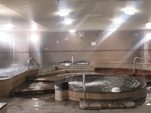 een badkamer met een groot bad met water bij Tsurusaki Hotel in Oita