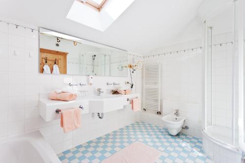 a white bathroom with a sink and a toilet at Hotel Schwarzer Adler mit Vilsalpsee Bähnchen in Tannheim