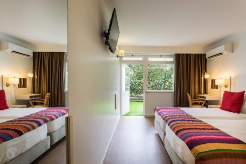a hotel room with two beds and a table at Hotel Londres Estoril / Cascais in Estoril