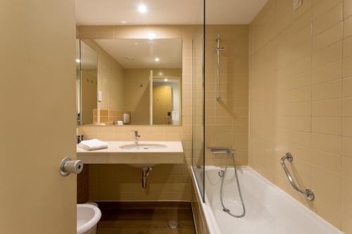 a bathroom with a sink and a tub and a toilet at Hotel Londres Estoril / Cascais in Estoril