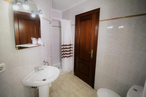 a bathroom with a sink and a toilet and a door at Hotel Restaurante Irubide in Alsasua