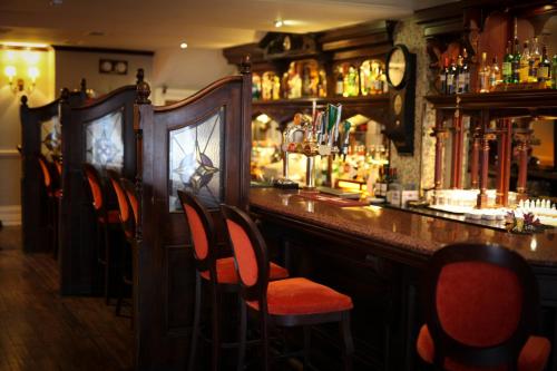 a bar with red chairs in a bar with a counter at Club House Hotel Kilkenny in Kilkenny