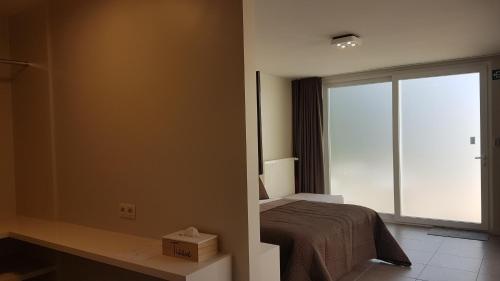 a bedroom with a bed and a large window at B&B Charles Cabour in De Panne