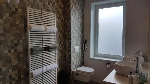 a bathroom with a sink and a toilet and a window at B&B Charles Cabour in De Panne