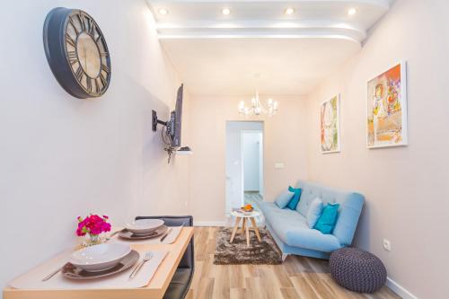 a living room with a blue couch and a clock on the wall at Apartments Summer Romance in Dubrovnik
