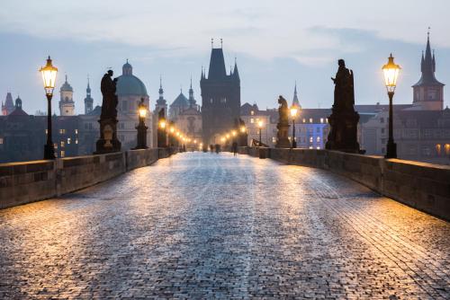 
a city street at night with a clock tower at MOODs Charles Bridge in Prague
