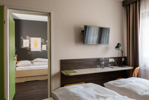 a reflection of a bedroom with two beds and a mirror at JUFA Hotel Graz Süd - Self Check-in in Graz