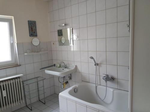 Baño blanco con bañera y lavamanos en modern-comfort-inn 1, en Kreuzau