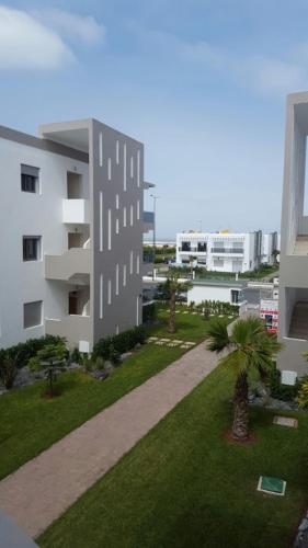 arial view of a building with a lawn and palm trees at Blanca Beach vue latérale sur mer in Sidi Rahal