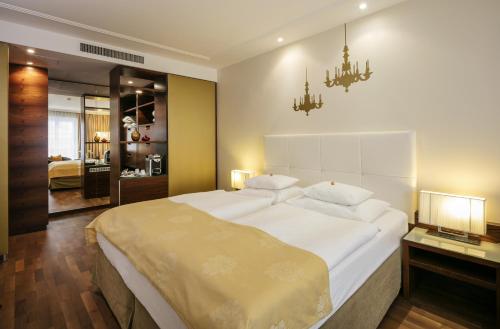 a bedroom with a large white bed with a chandelier at Boutique Hotel Das Tigra in Vienna