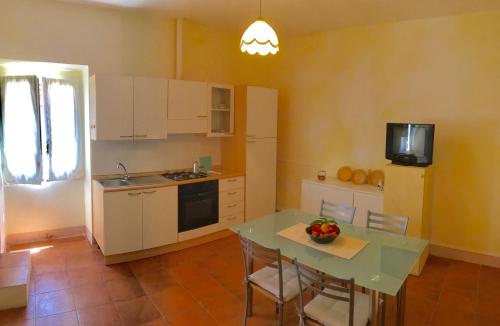 eine Küche mit einem Tisch mit Stühlen und einem TV in der Unterkunft Da Lucio - Appartamento tipico nel centro storico di Sorso in Sorso
