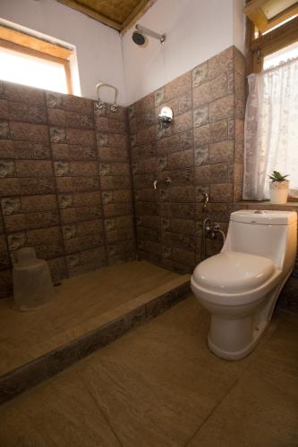 a bathroom with a toilet and a shower with a tub at PaliGhar Farmstay in Kalimpong