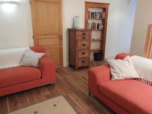 a living room with two red chairs and a book shelf at Vergecosse in Vergisson