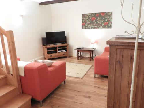 a living room with a red couch and a television at Vergecosse in Vergisson