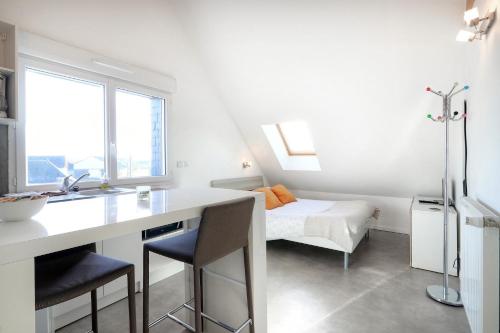 a white kitchen with a desk and a bed at Les Gîtes d'Emilie in Melesse