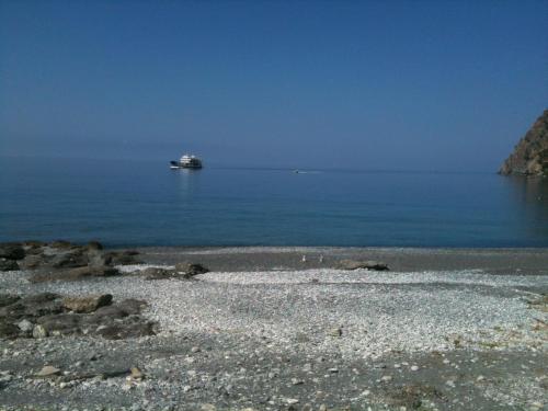 a ship in the water with a rocky beach at Faragi in Agia Roumeli
