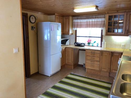 a kitchen with a white refrigerator and wooden cabinets at Vegby Bolsgård "Lillstugan" in Moheda