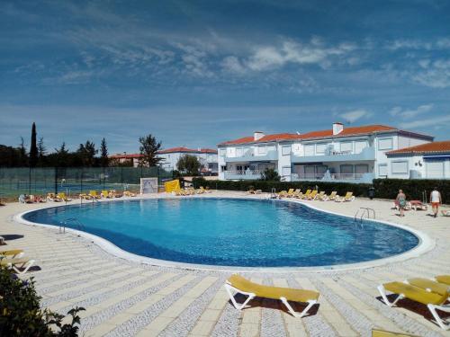 a large swimming pool with chairs and a building at Apartment Oásis Comfort in Portimão