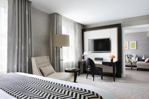 a hotel room with a bed and a desk and a living room at Rosewood Hotel Georgia in Vancouver
