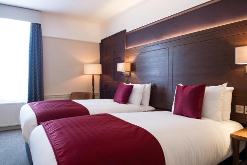 two beds in a hotel room with red and white at Miller & Carter Maidstone by Innkeeper's Collection in Maidstone