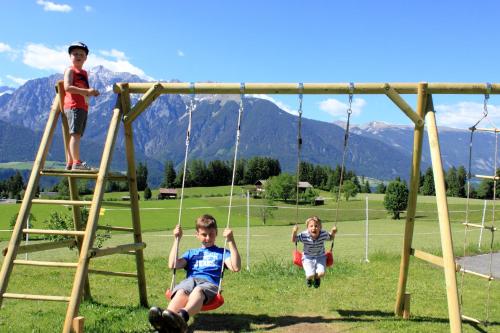 two children playing on swings in a park at Huaberhof Weerberg in Weerberg