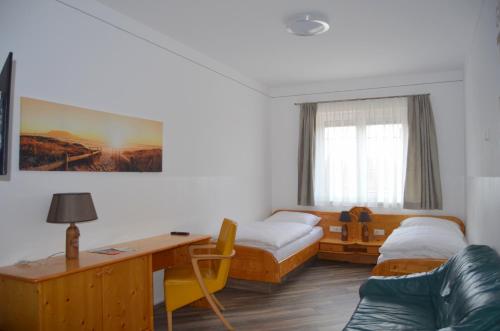 Zimmer mit 2 Betten, einem Schreibtisch und einem Sofa in der Unterkunft Pension zum Strell in Hollabrunn