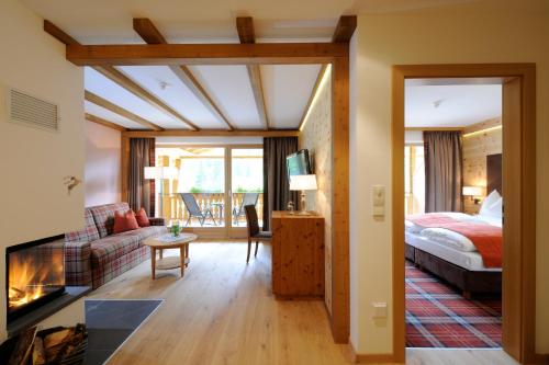 a bedroom with a bed and a living room with a fireplace at BAD MOOS - Aqua Spa Resort in Sesto