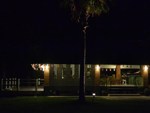 a palm tree in front of a building at night at Phuket Campground in Mai Khao Beach