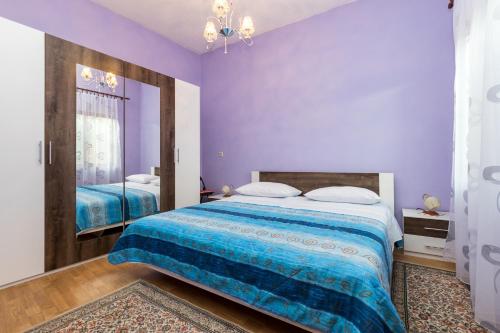 a bedroom with purple walls and a large bed at apartments TONI with free parking in Ka&scaron;tela