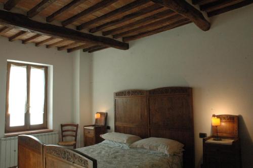 een slaapkamer met een bed met een houten hoofdeinde en een raam bij La Palazzetta di Luca e Flavio in Castelnuovo dellʼAbate