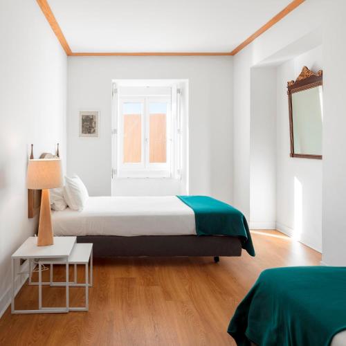 um quarto branco com uma cama e uma janela em Palácio Camões - Lisbon Serviced Apartments em Lisboa