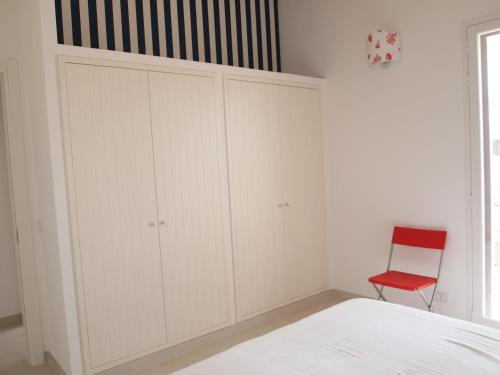a bedroom with white cabinets and a red chair at La Casa Di Pina in Sampieri