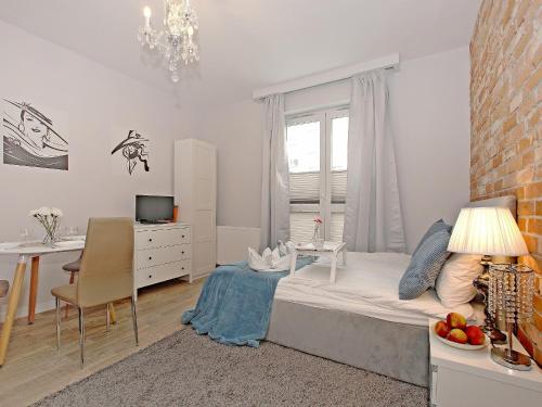a white bedroom with a bed and a desk and a table at Apartament Starogdański 6 in Gdańsk