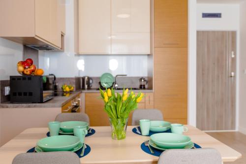 a kitchen with a table with plates and flowers on it at Resort Apartamenty Klifowa Rewal 1 in Rewal